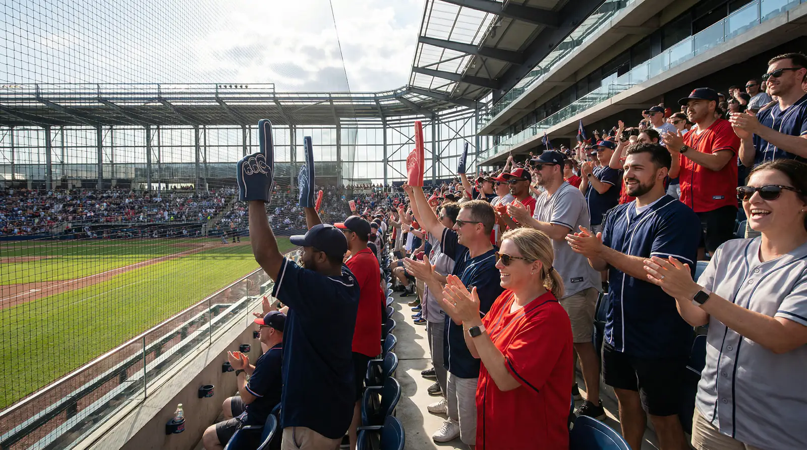 Baseball fans wearing team jerseys at London Stadium during the MLB London Series with the pitch visible in the background